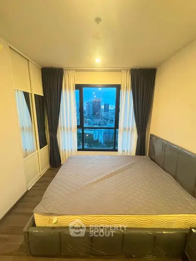 Modern bedroom with city view, featuring a large window and stylish decor.