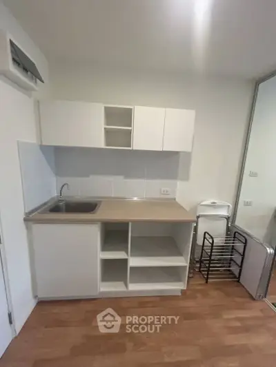Compact kitchen with modern cabinetry and wooden flooring in a cozy apartment