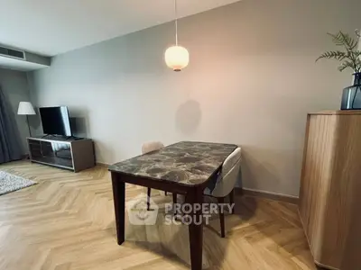 Modern living room with stylish dining table and TV, featuring elegant wooden flooring.
