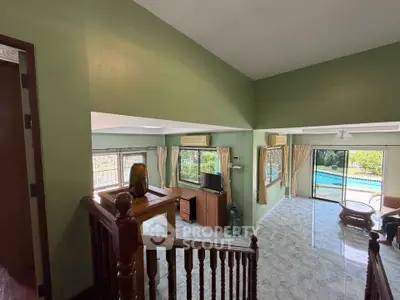 Spacious living room with pool view and elegant wooden staircase in a modern home.
