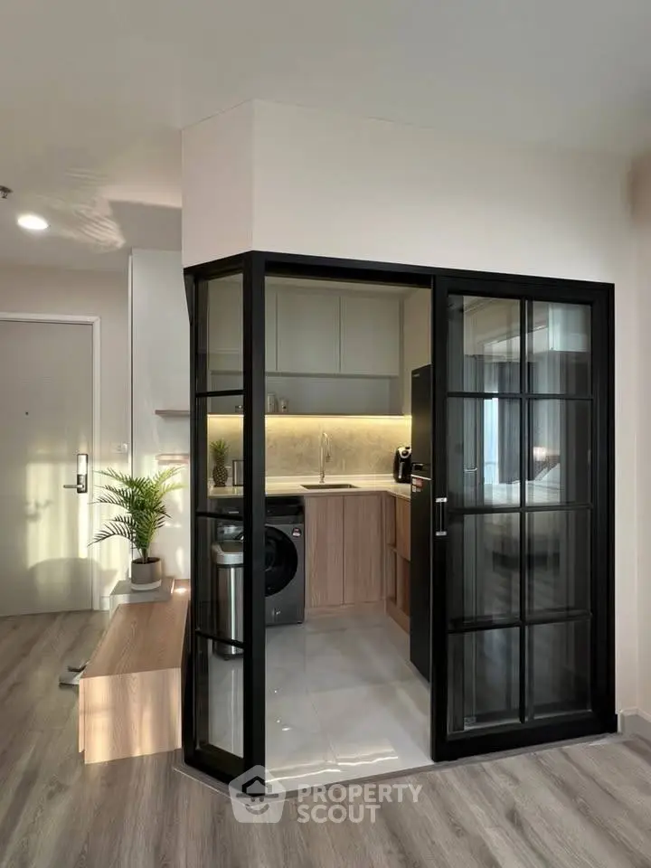 Modern compact kitchen with glass enclosure and washing machine in stylish apartment.