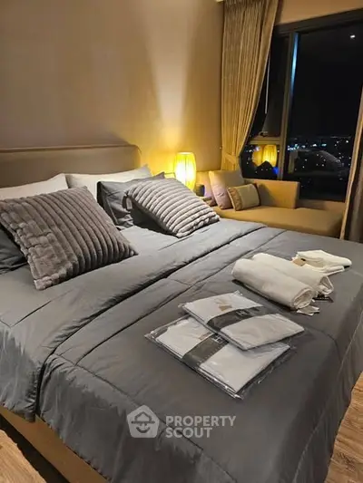 Luxurious bedroom with cozy lighting and city view, featuring plush bedding and elegant decor.