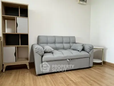 Modern living room with stylish gray sofa and wooden shelving unit.