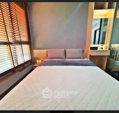 Cozy bedroom with modern decor and ample natural light from large windows.