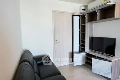 Modern living room with sleek black leather sofa and stylish entertainment unit.