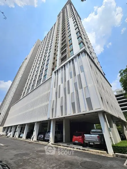 Modern high-rise building with parking area and clear blue sky