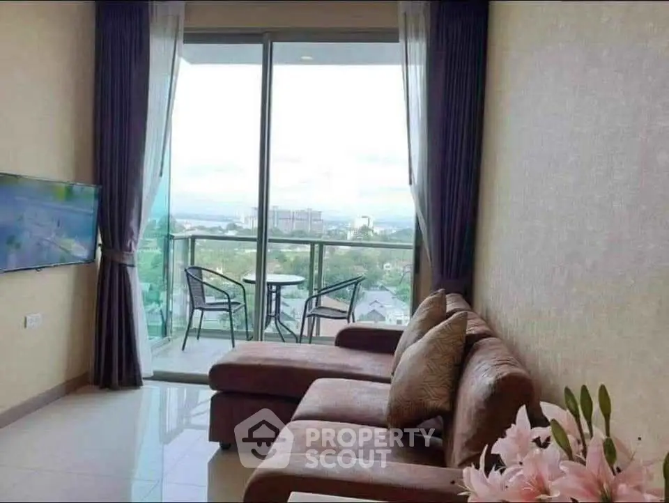 Modern living room with large windows and balcony offering stunning city views.