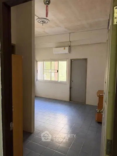Spacious room with tiled floor and natural light, ideal for versatile use in a residential property.