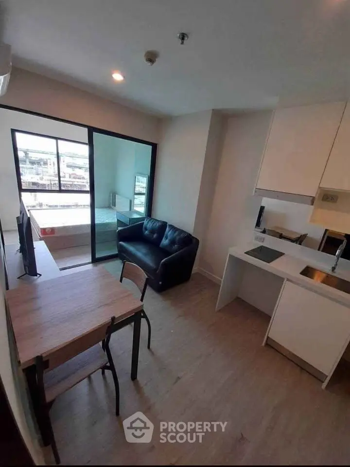 Modern open-plan living room with sleek kitchen and balcony view, perfect for urban living.