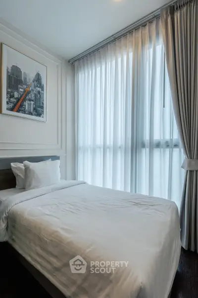 Modern bedroom with large window and cityscape artwork, offering natural light and cozy ambiance.