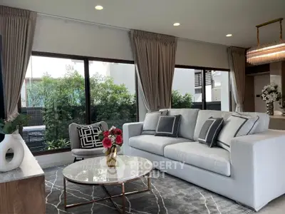 Elegant living room with modern decor and large windows overlooking greenery.