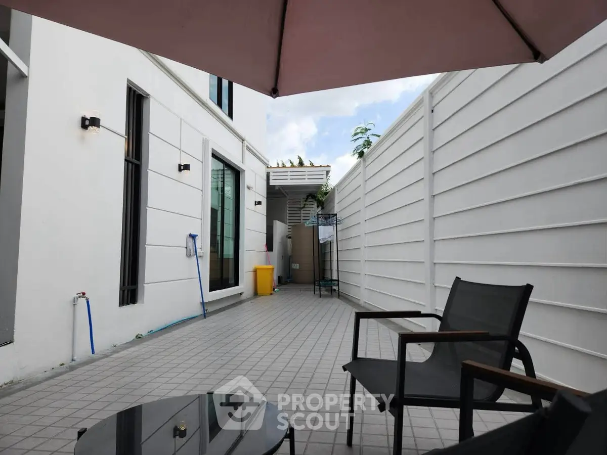 Charming outdoor patio with modern seating and privacy fence, perfect for relaxation and entertaining.