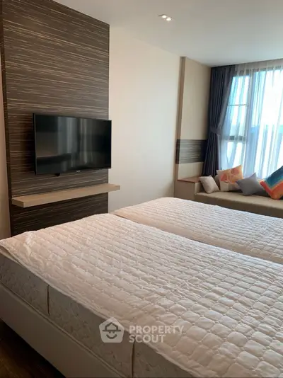 Modern bedroom with twin beds and wall-mounted TV in a stylish apartment.