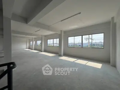Spacious open-plan industrial space with large windows and natural light, ideal for commercial use.
