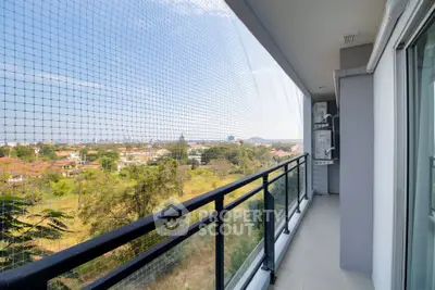 Spacious balcony with safety netting and scenic view of lush greenery and distant hills.