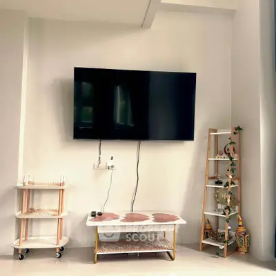 Modern living room with wall-mounted TV and stylish shelving units.