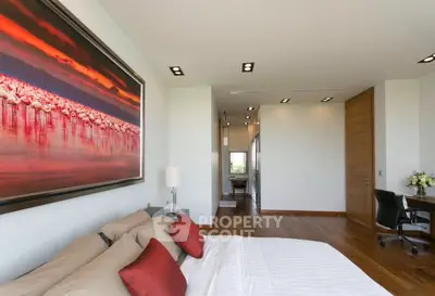 Luxurious bedroom with elegant decor and stunning artwork, featuring a cozy workspace and modern lighting.