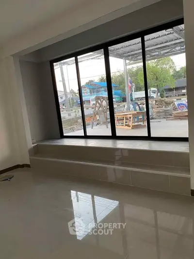 Spacious room with large window offering natural light and outdoor view, ideal for modern living.