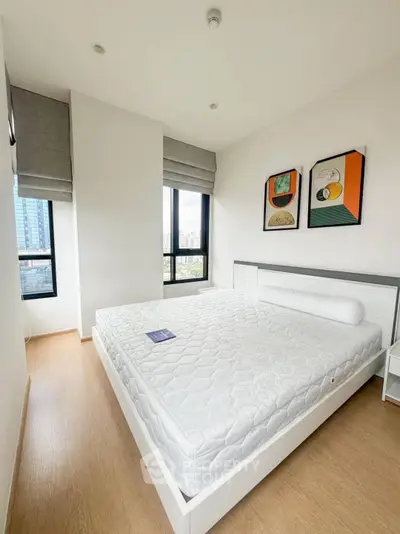 Spacious bedroom with large windows and modern decor in a high-rise apartment.