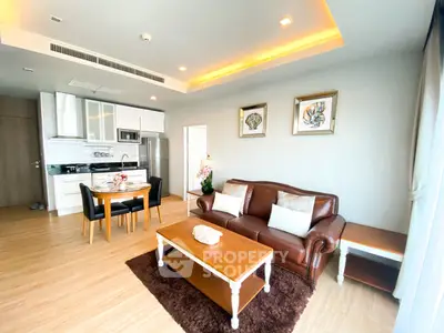 Modern living room with stylish decor, leather sofa, and open kitchen layout in a bright apartment.