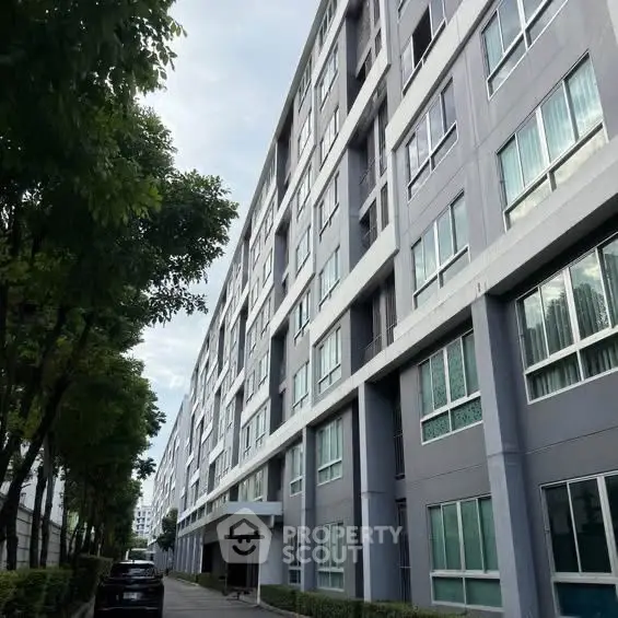 Modern apartment building exterior with lush greenery and sleek design.