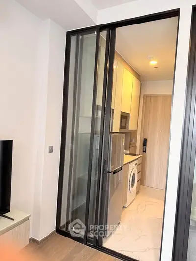 Modern kitchen with sleek appliances and sliding glass door in a compact apartment.