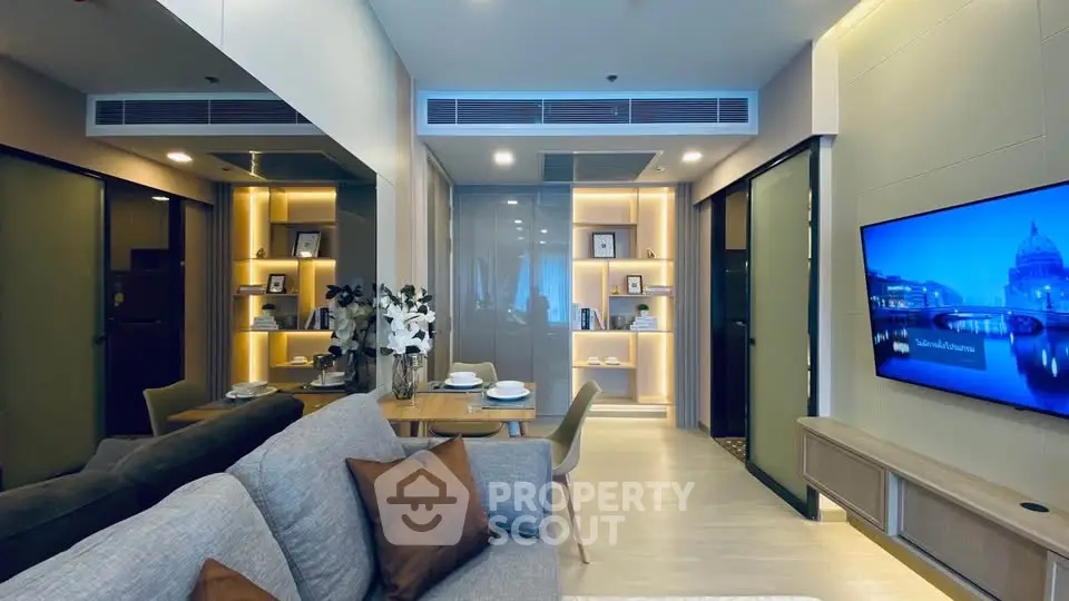 Modern living room with elegant decor and built-in shelving, featuring a cozy seating area and wall-mounted TV.