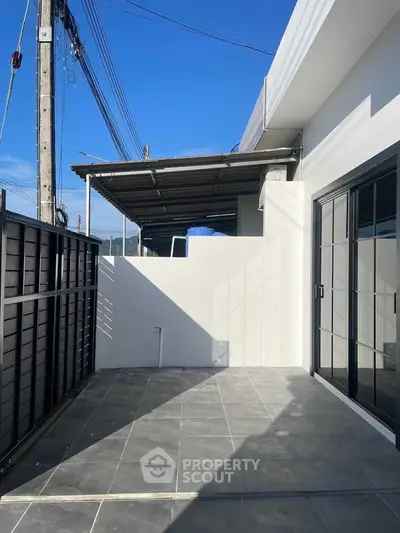 Modern outdoor patio with sleek tiles and sliding glass doors, perfect for relaxation and entertainment.