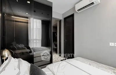 Modern bedroom with sleek design, featuring mirrored wardrobe and air conditioning unit.