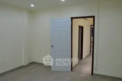 Spacious empty room with open door and modern flooring, ideal for customization.