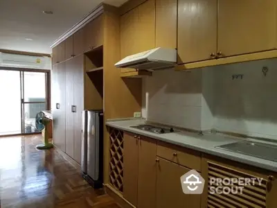 Spacious kitchen with wooden cabinets and modern appliances in a cozy apartment.