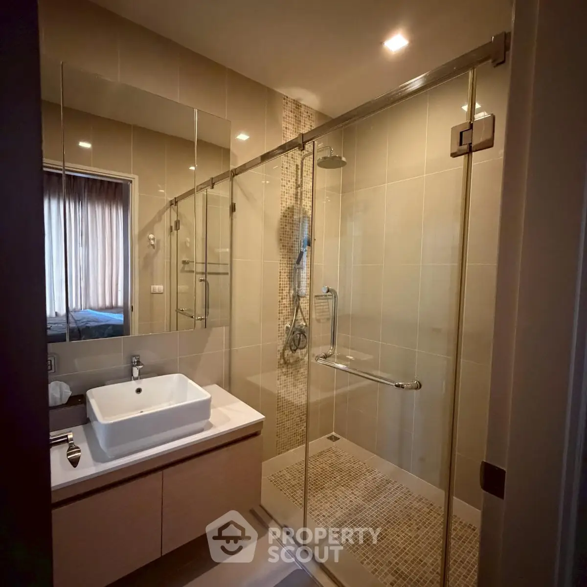 Modern bathroom with glass shower and sleek vanity in contemporary apartment.
