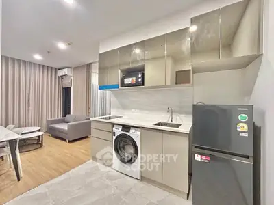 Modern open-layout kitchen with sleek appliances and cozy living area in a stylish apartment.