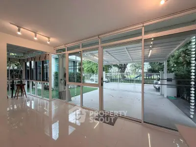 Spacious modern living room with large glass doors opening to a covered patio and lush garden view.