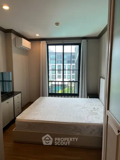 Modern bedroom with large window and air conditioning in urban apartment