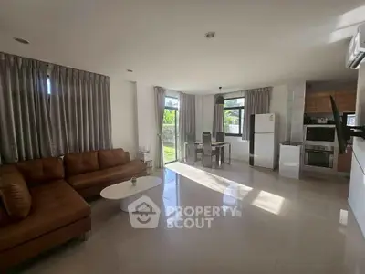 Spacious open-plan living room with modern kitchen and dining area, featuring sleek appliances and ample natural light.