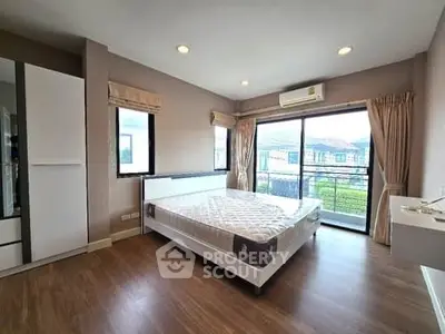 Spacious bedroom with large windows and balcony access, featuring modern design and ample natural light.