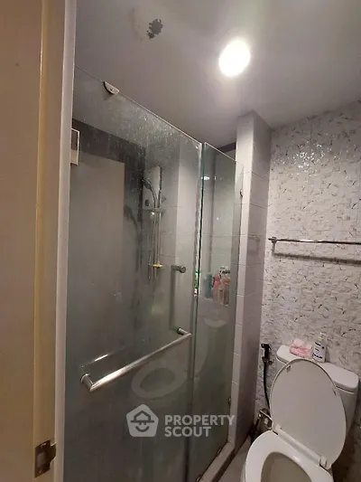 Modern bathroom with glass shower and tiled walls, featuring a sleek design.