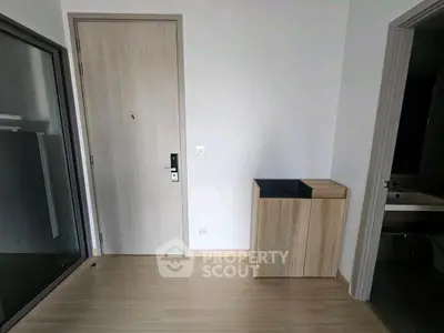 Modern minimalist entrance with sleek wooden flooring and compact storage unit.