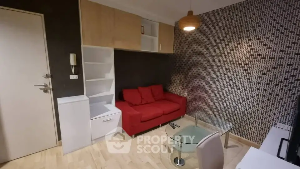 Modern living room with red sofa, geometric wallpaper, and stylish furniture.