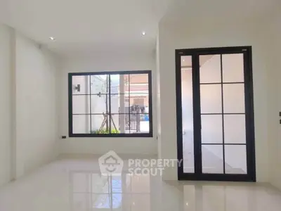 Spacious modern living room with large windows and sleek black frames, offering abundant natural light.