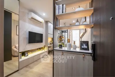 Modern living room with stylish decor and built-in shelving, featuring a sleek TV setup and elegant lighting.