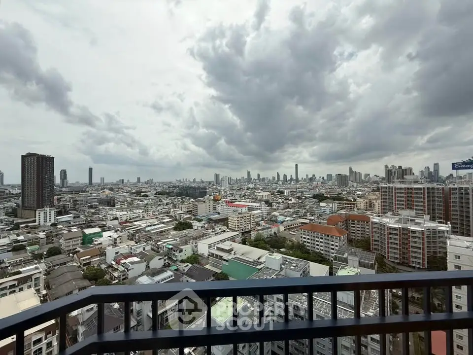 Stunning cityscape view from a high-rise balcony showcasing urban skyline under dramatic clouds.