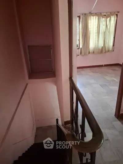 Charming interior view showcasing staircase leading to a sunlit room with large window and curtains.