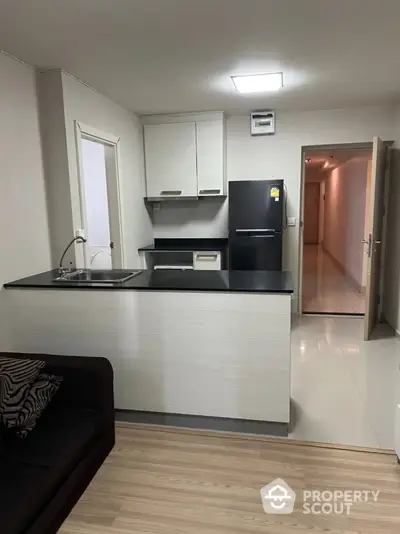 Modern kitchen with sleek black countertops and white cabinets in a cozy apartment.