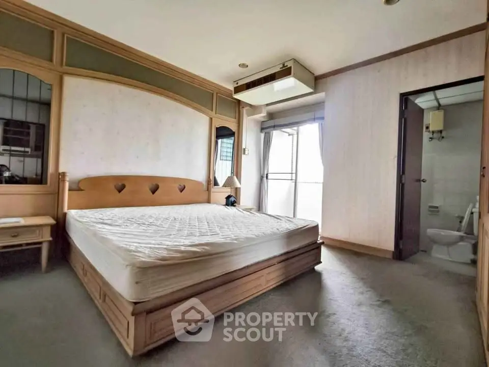 Spacious bedroom with ensuite bathroom and balcony access in modern apartment.