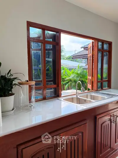 Charming kitchen with open window view and sleek wooden cabinetry
