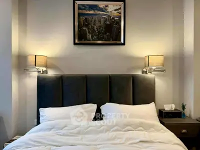 Luxurious bedroom with elegant lighting and cityscape artwork above bed.