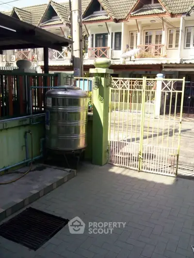 Charming townhouse exterior with gated entrance and stainless steel water tank.