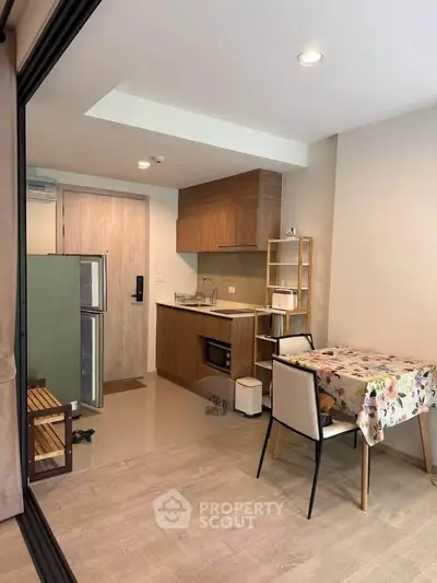 Modern compact kitchen with dining area in a cozy apartment, featuring wooden cabinetry and stylish decor.